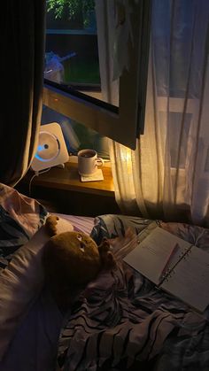 a teddy bear laying on top of a bed next to a window with curtains over it