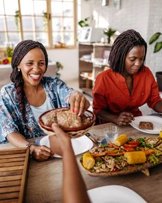 three women sitting at a table with food in front of them and one woman holding a plate