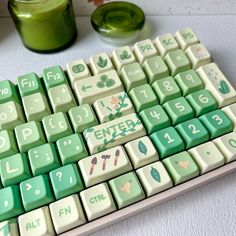 a green and white computer keyboard sitting on top of a table next to a cup