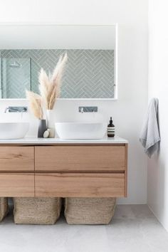 a bathroom with two sinks and a large mirror above the sink is next to some baskets