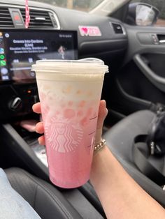 a person holding a cup in their hand while sitting in the driver's seat of a car