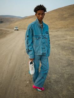 a young man standing in the middle of a dirt road