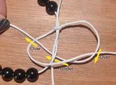 a string with beads connected to each other on a table next to a person's hand