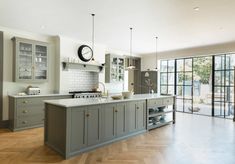 a large kitchen with wooden floors and gray cabinets