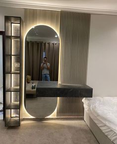 a man taking a selfie in the reflection of a mirror on a wall next to a bed