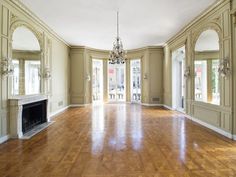 an empty room with wood floors and chandelier