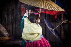 two people are hugging under an umbrella in the rain