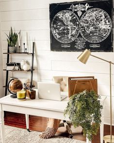 a white desk with a laptop on it in front of a black and white map