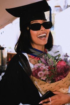 a woman in graduation cap and gown holding flowers