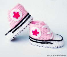 two crocheted pink and white baby shoes with red stars on the top, one has a black stripe around the bottom