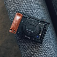 a wooden camera sitting on top of a gray couch next to a person's arm