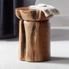 a wooden stool sitting on top of a white floor next to a black curtained window