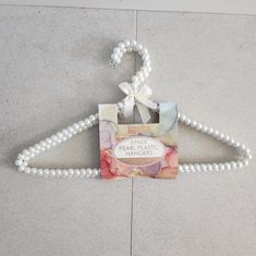 a white beaded hanger with pearls attached to it on the floor next to a wall