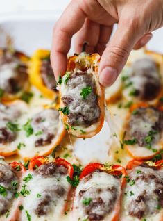 a person is dipping some food into a casserole dish with meatballs and cheese