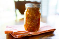 a glass jar filled with pickles sitting on top of a table