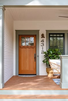 a porch with a chair and potted plant on the front step next to it