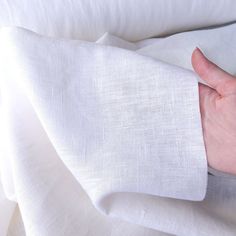 a person's hand on top of a white sheet