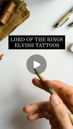 lord of the rings elvish tattoos is holding a pen in his hand and surrounded by other office supplies