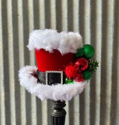 a red and black santa hat on top of a metal pole next to a corrugated wall