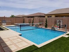 a backyard with a pool, basketball hoop and artificial grass on the lawns in front of it