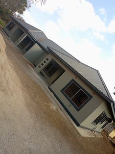 a house on the side of a hill with a dirt road leading up to it