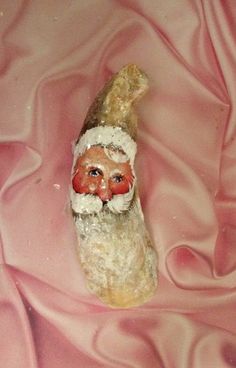 a small figurine is sitting on a pink satin sheet with a santa clause hat