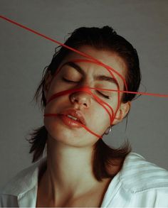 a woman with her eyes closed and red string in front of her face as if she was tied to something