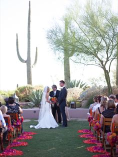 a bride and groom standing at the end of their wedding ceremony in front of cacti