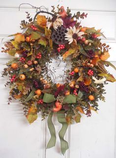 a wreath with leaves, berries and acorns hanging on a door