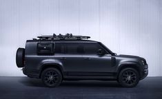 an suv is parked in front of a wall with skis on it's roof