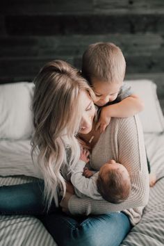 a woman holding a baby while laying on top of a bed