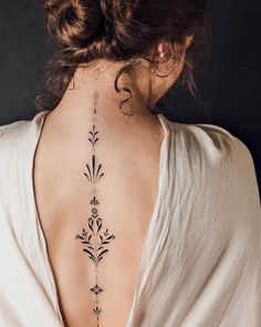 the back of a woman's neck with an intricate tattoo design on her left side