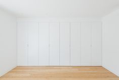 an empty room with white walls and wooden floors