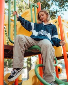 a woman sitting on top of a playground slide