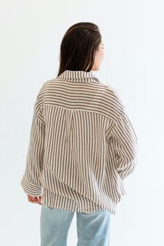 Stay cool and stylish this summer with our Zuma Button Down, featuring pretty iridescent buttons and a raw hem. This super lightweight top offers an effortless, relaxed, and roomy fit, making it perfect for warm weather. Best of all? Its 100% cotton! Wear it buttoned up for a polished look or unbuttoned over a swimsuit or tank for a breezy, casual vibe. This versatile piece is a must have summer staple! Malibu Collection FIT Relaxed Roomy Fit Iridescent Buttons High-Low Raw Hem Savannah is 5'8 W Linen Tops With Button Closure For Vacation, Striped Button Tops For Vacation, Relaxed Striped Tops For Spring, Oversized Button Closure Top For Loungewear, Oversized Loungewear Tops With Button Closure, Spring Striped Loungewear Shirt, Striped Long Sleeve Linen Tops, Striped Shirt For Spring Loungewear, Spring Striped Shirt For Loungewear