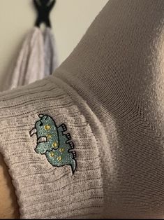 the back of a woman's sweater with a dinosaur embroidered on it