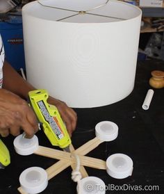 a person is working on some crafting items with glue and wood dows in front of a lamp