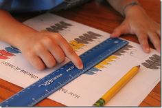 a child is drawing on some paper with a pencil and ruler in front of them