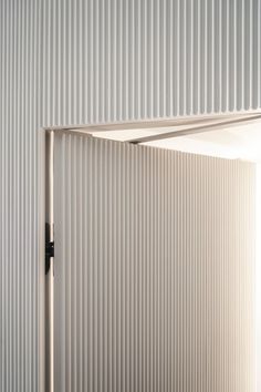 an open door in a white wall with vertical blinds