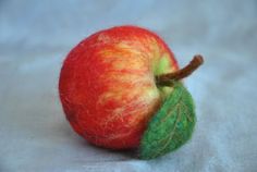 an apple with a green leaf on the end and a red apple in the middle