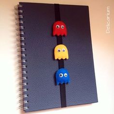 a spiral notebook with three pacman magnets attached to it