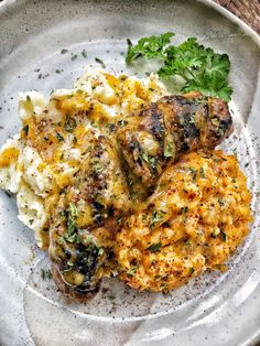 a white plate topped with meat and pasta covered in herbs next to parmesan cheese