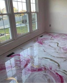 a room that has been painted with pink and white swirls on the floor in front of two windows