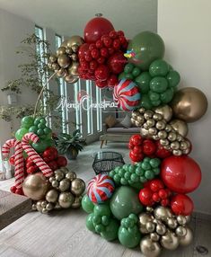 the balloon arch is decorated with red, green and gold balloons that resemble candy canes