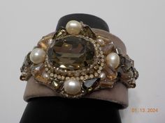 "Vintage sparkly cuff bracelet. 1 5/8\"L, 7 1/2\"W. Faux suede with satin lining on the inside. Large faceted crystal in the center 3/4\" x 1\" surrounded by faux pearls, clear rhinestones, opalescent rhinestones, smokey gray crystals, and more. Gems/rhinestones, etc. are all present, intact, & prong set, except the pearls. Pearls are not prong set. There is a slight tint of pink on the center/edge of the cuff. Otherwise, excellent vintage condition. PLEASE READ THE DESCRIPTION BEFORE PURCHASING Adjustable Jeweled Crystal Bracelet For Formal Occasions, Adjustable Bedazzled Formal Jewelry, Beaded Cuff Jewelry For Party, Formal Adjustable Embellished Jewelry, Adjustable Rhinestone Crystal Bracelet For Evening, Elegant Adjustable Jeweled Cuff Bracelet, Party Cuff Beaded Jewelry, Party Beaded Cuff Jewelry, Adjustable Rhinestone Cuff Bracelet For Weddings