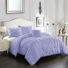 a bed with purple comforter and pillows in a room