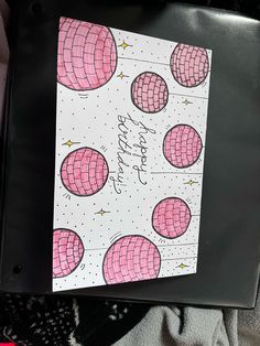 a black binder with pink and white balls on it, next to a card that says happy birthday