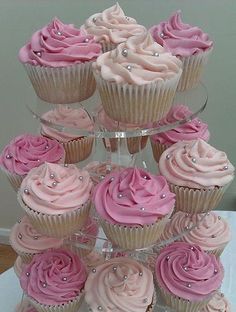 there are many cupcakes stacked up on the cake stand with pink frosting