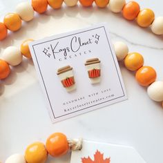 an orange and white beaded necklace with two small cup shaped earrings on top of it