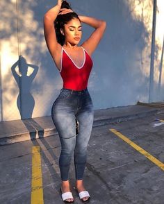 a woman in high rise jeans and a red tank top is posing for the camera